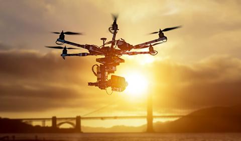 un drone survolant un pont suspendu au soleil couchant