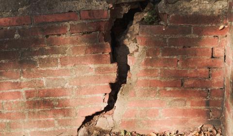 Un mur en briques fendu d'une large fissure