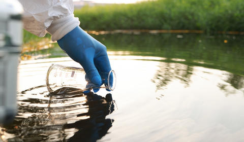 PFAS : un ou une scientifique prélevant un échantillon pour analyses dans un cours d'eau.