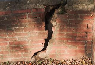 Un mur en briques fendu d'une large fissure