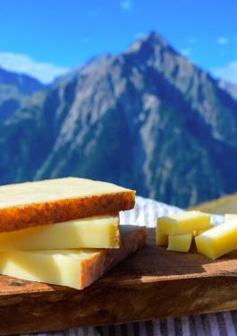 Une planche de fromage Comté AOP devant les montagnes du Jura en arrière-plan