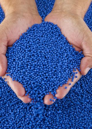 mains tenant des granules plastiques bleues