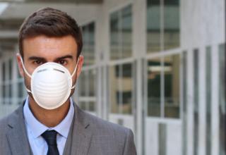 Jeune cadre portant un costume et un masque anti-pollution