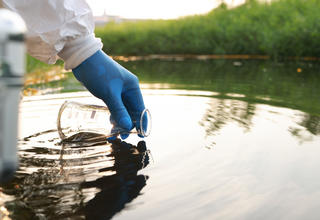 PFAS : un ou une scientifique prélevant un échantillon pour analyses dans un cours d'eau.